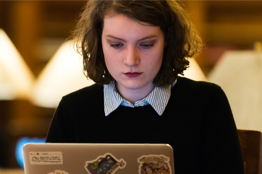 A University of Rochester student sitting at a table, focused on her laptop while studying.